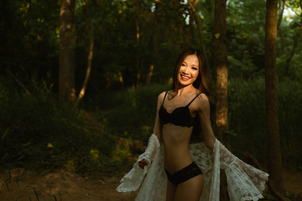 woman in black lingerie and white sheer robe in a forest for her outdoor boudoir shoot.