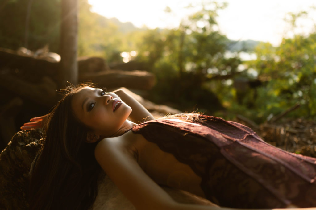 Woman in lacy bodysuit lingerie lying outside on her back.