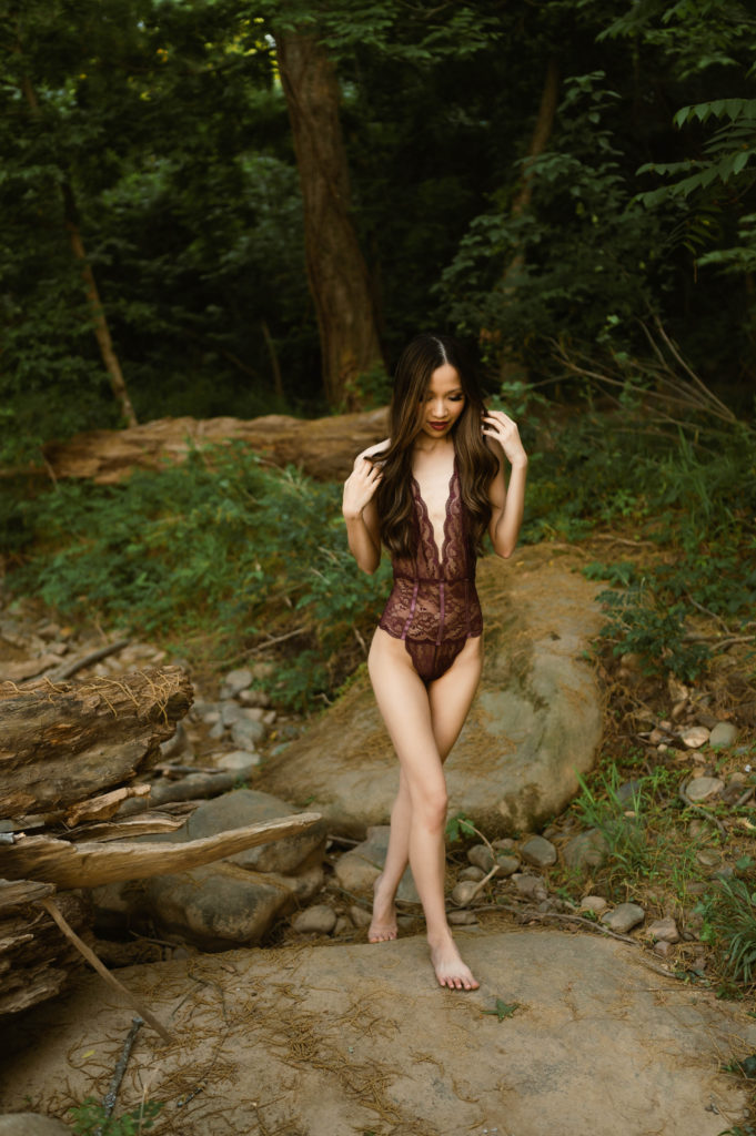 Woman in lace lingerie body suit outside.