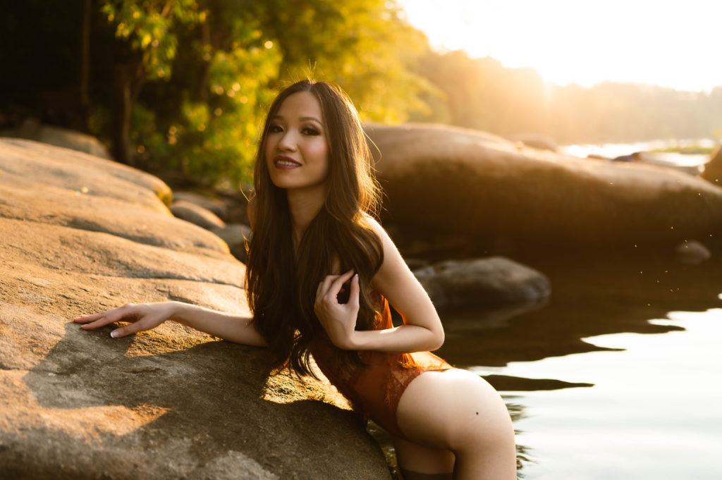 Woman in lingerie in the water, leaning against the rocks.