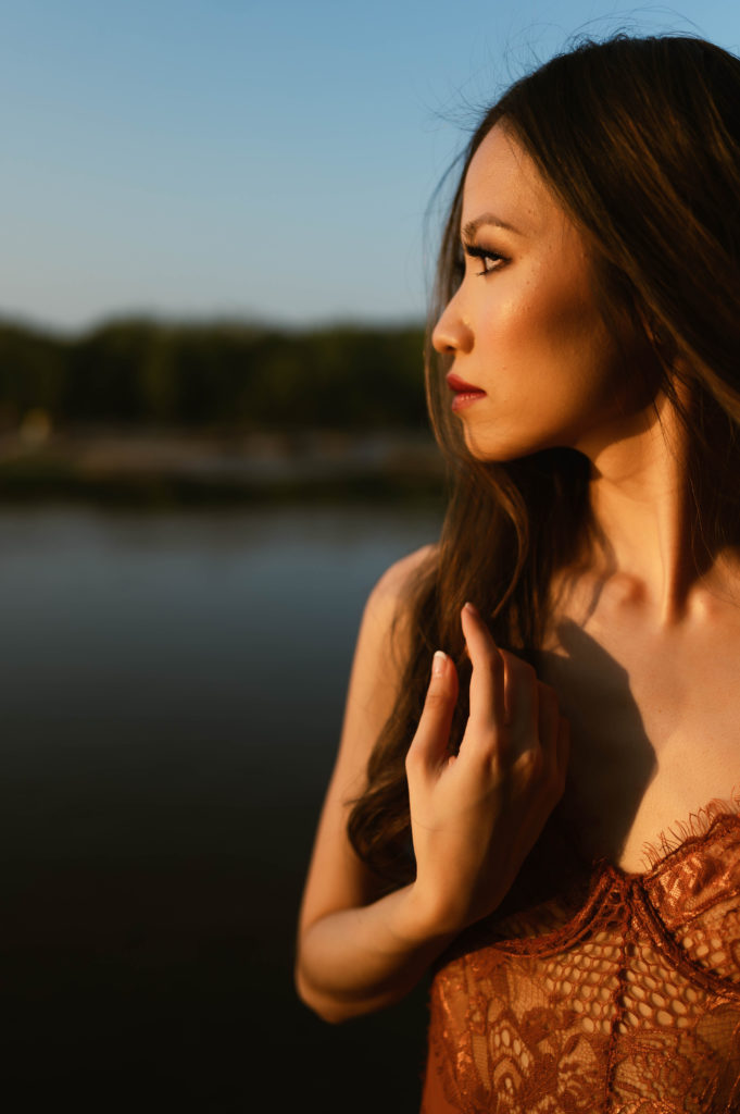 Woman in lace lingerie outside, gazing off into the sunset.