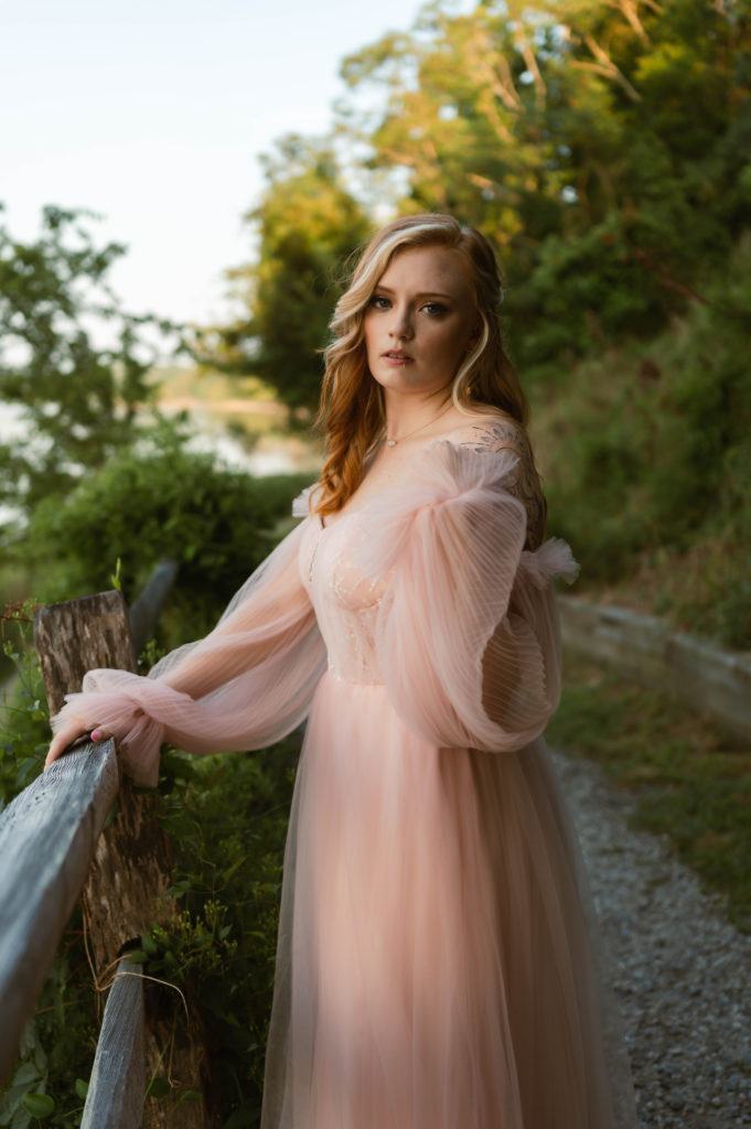 Redhead woman in a pale pink dress outside on a path. 