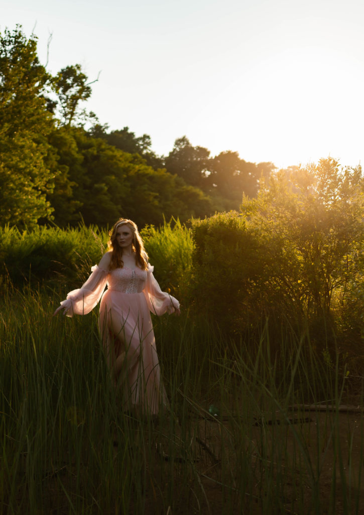 Woman in pale pink tulle dress running through a high grass field in Richmond, Virginia. 