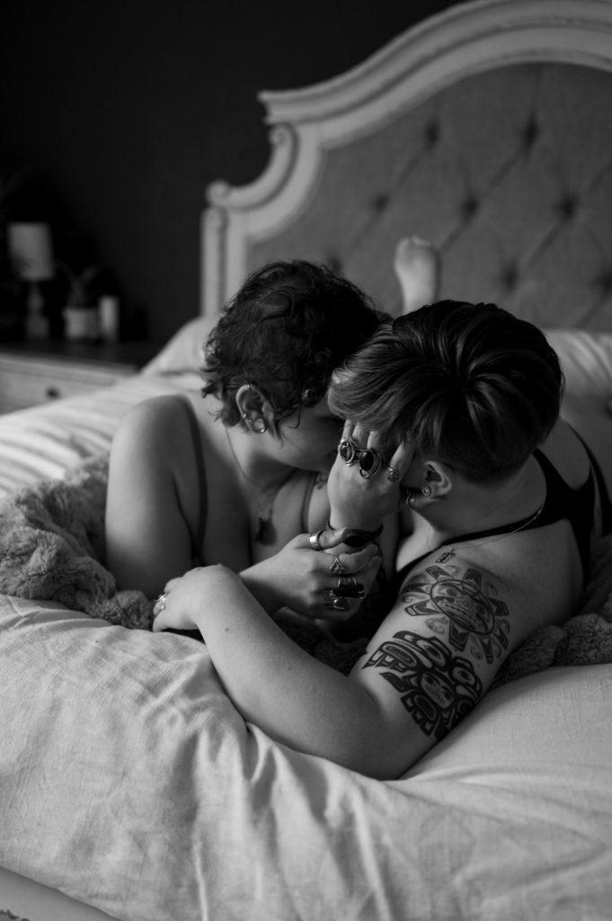 Black and white intimate image of two women on the bed, wrapped up in each other's arms. | Virginia Sensual Photography