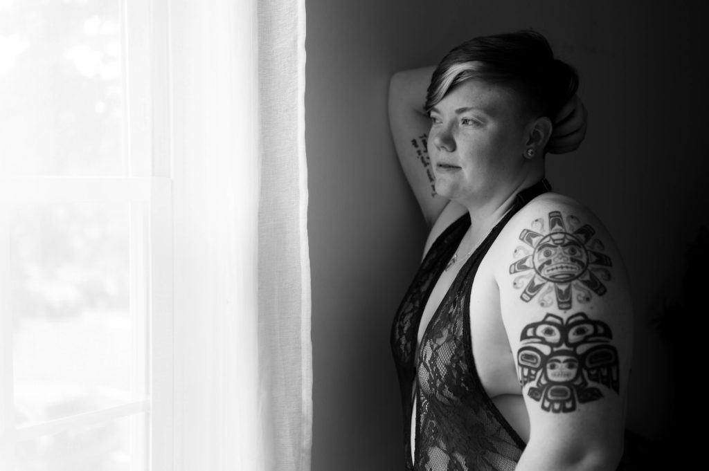 Black and white image of a woman with short hair looking out of a window.