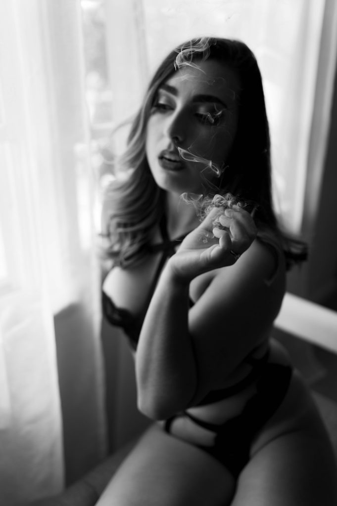 Black and white image of a woman in lingerie smoking. 