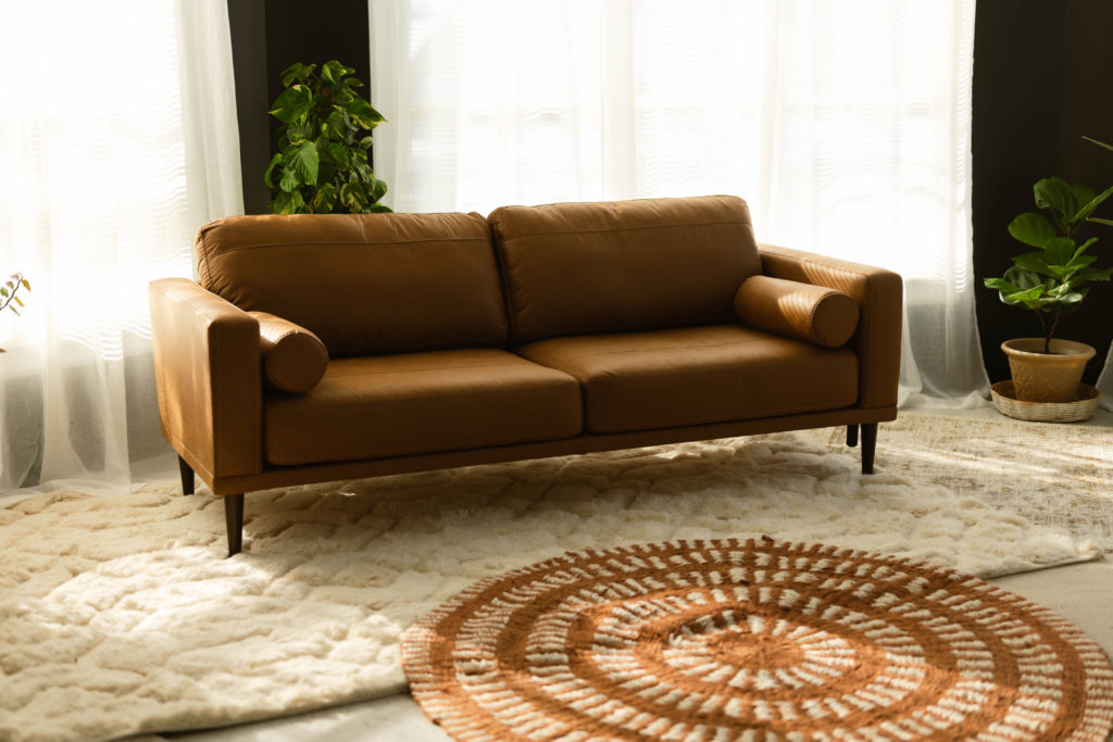 A leather couch surrounded by rugs and plants at this beautiful new studio for a boudoir photographer.