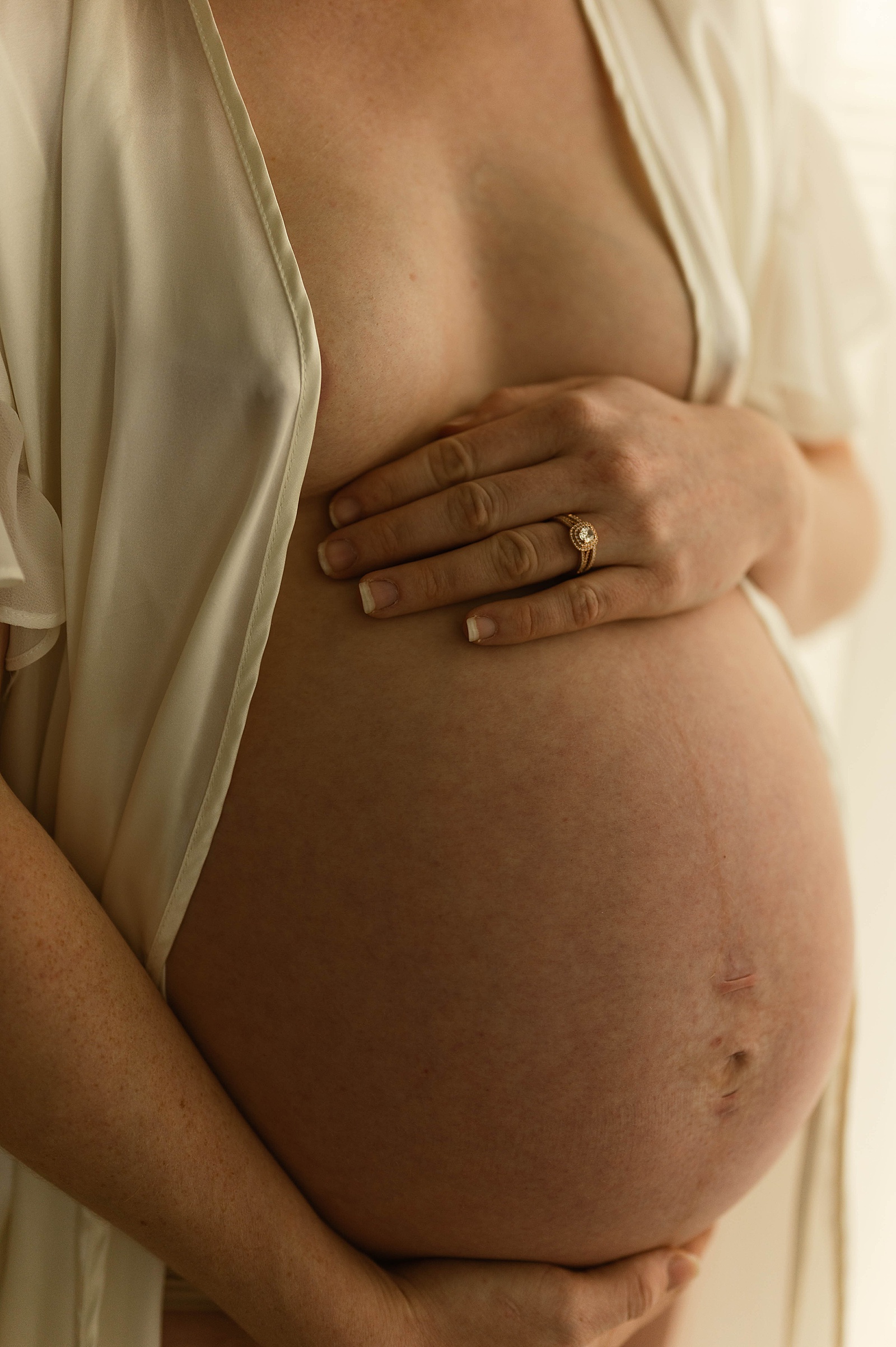 Woman putting her hand on her naked belly while wearing a robe 