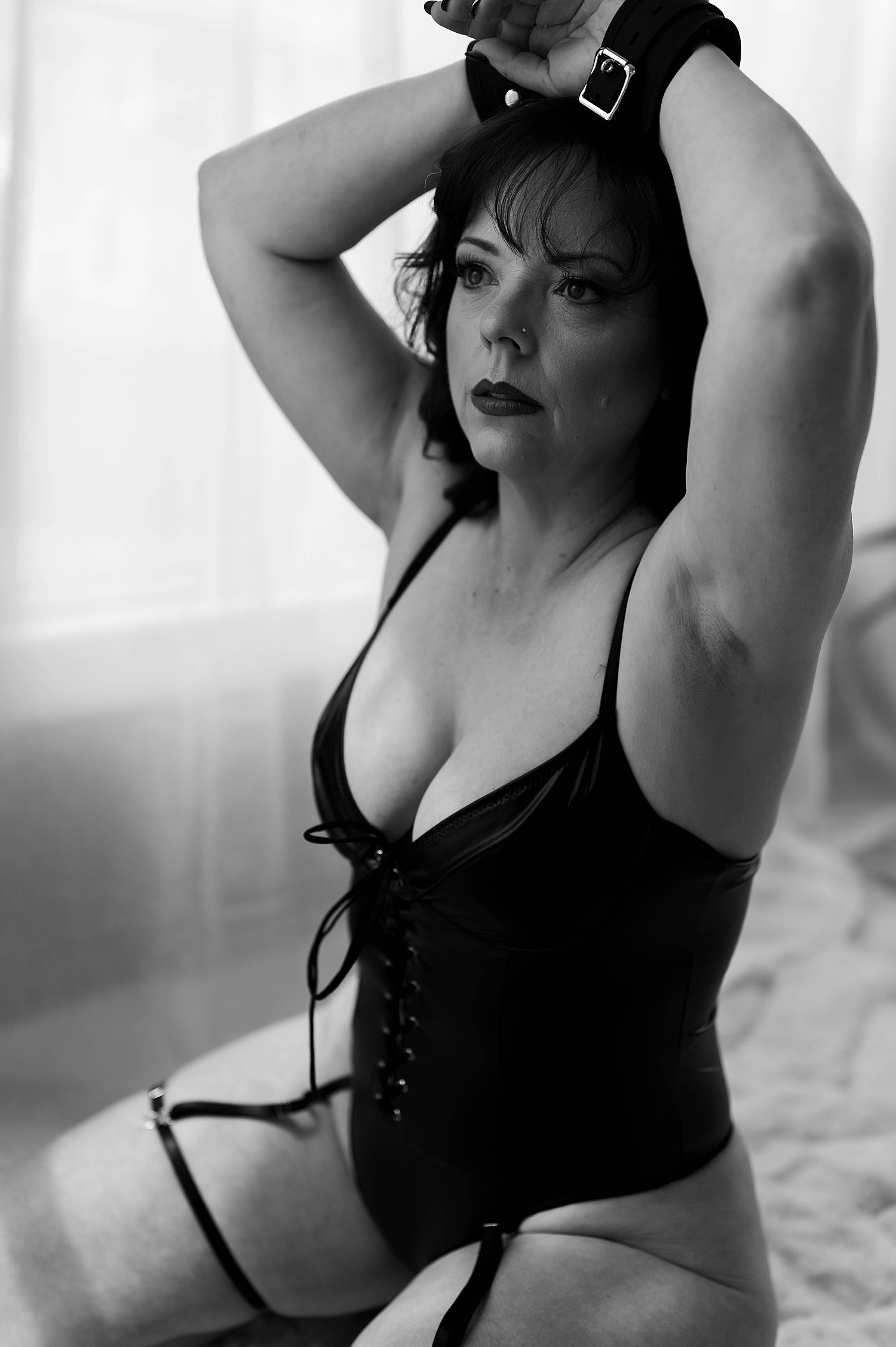 Woman in black leather bodysuit in handcuffs for empowering session with Tease by Hannah Louise