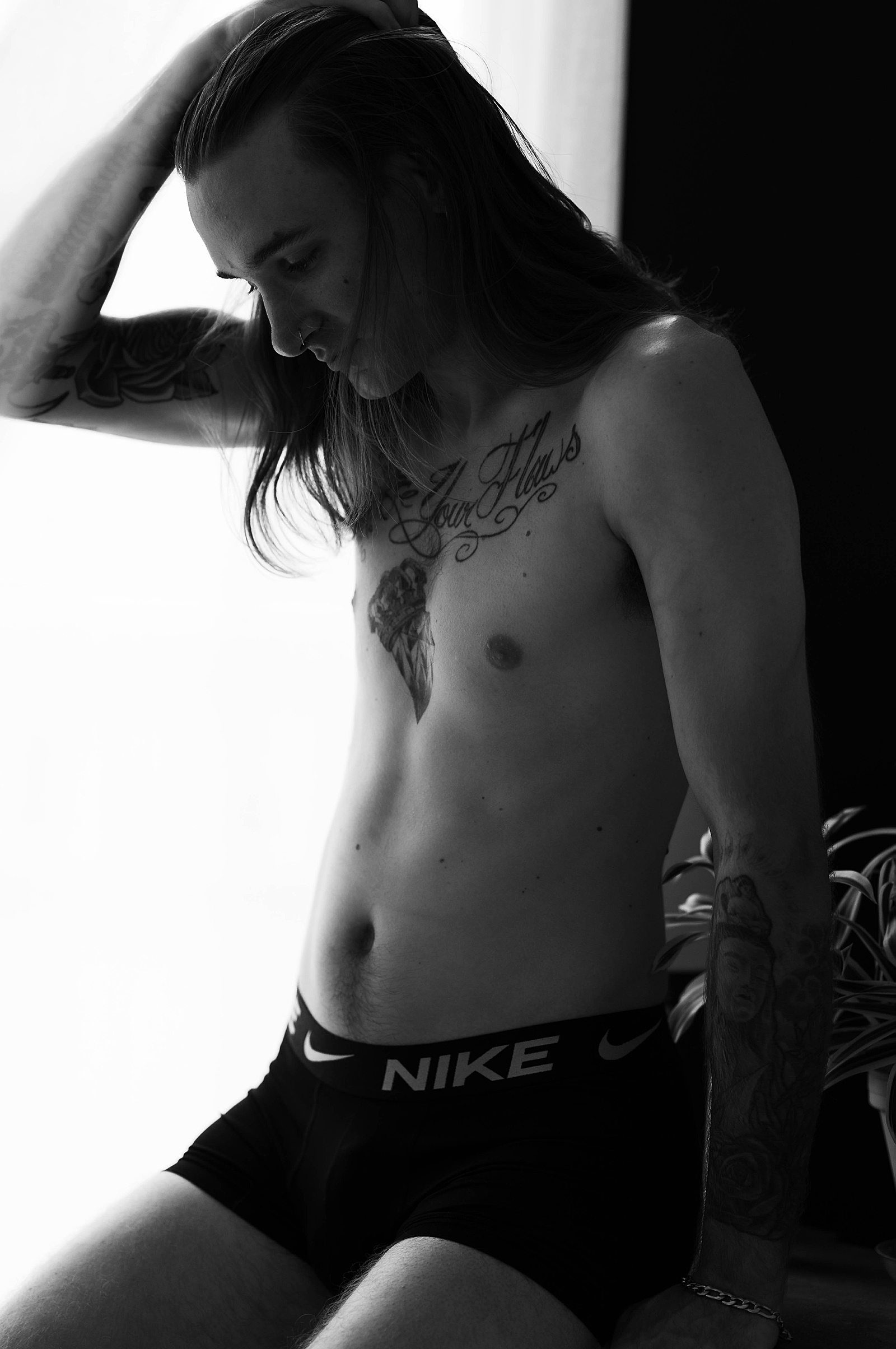 man with long hair and tattoos by a window by Tease by Hannah Louise photographer