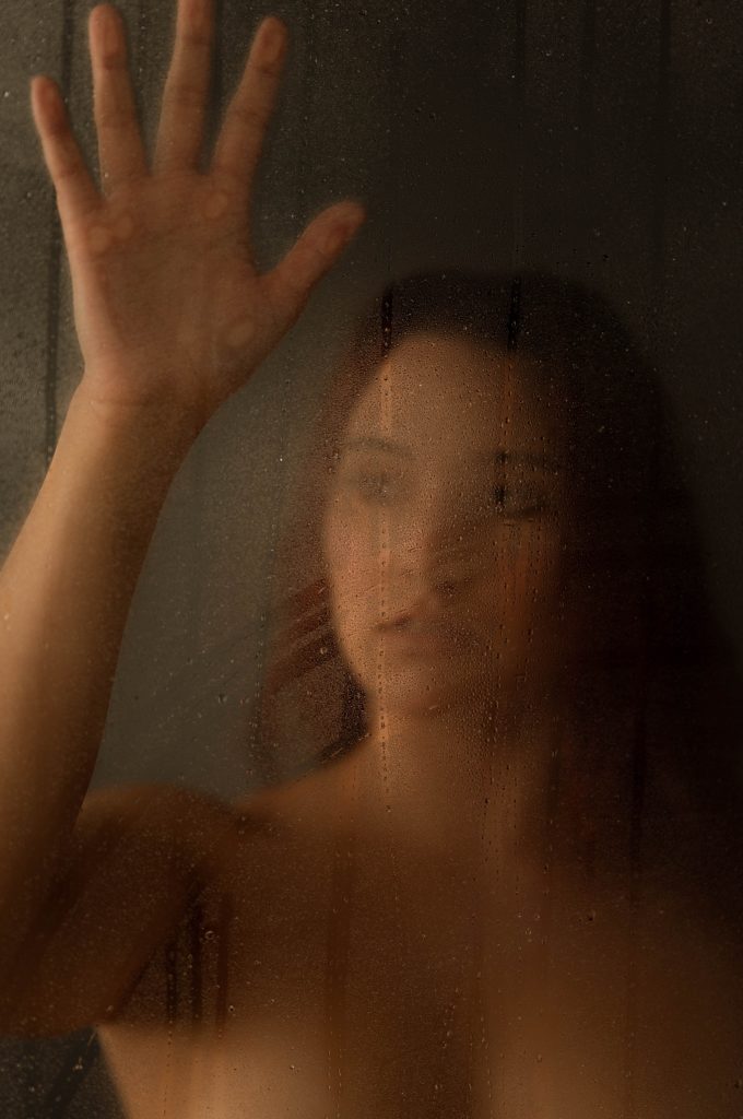 Woman behind a shower door for sensual photo shoot