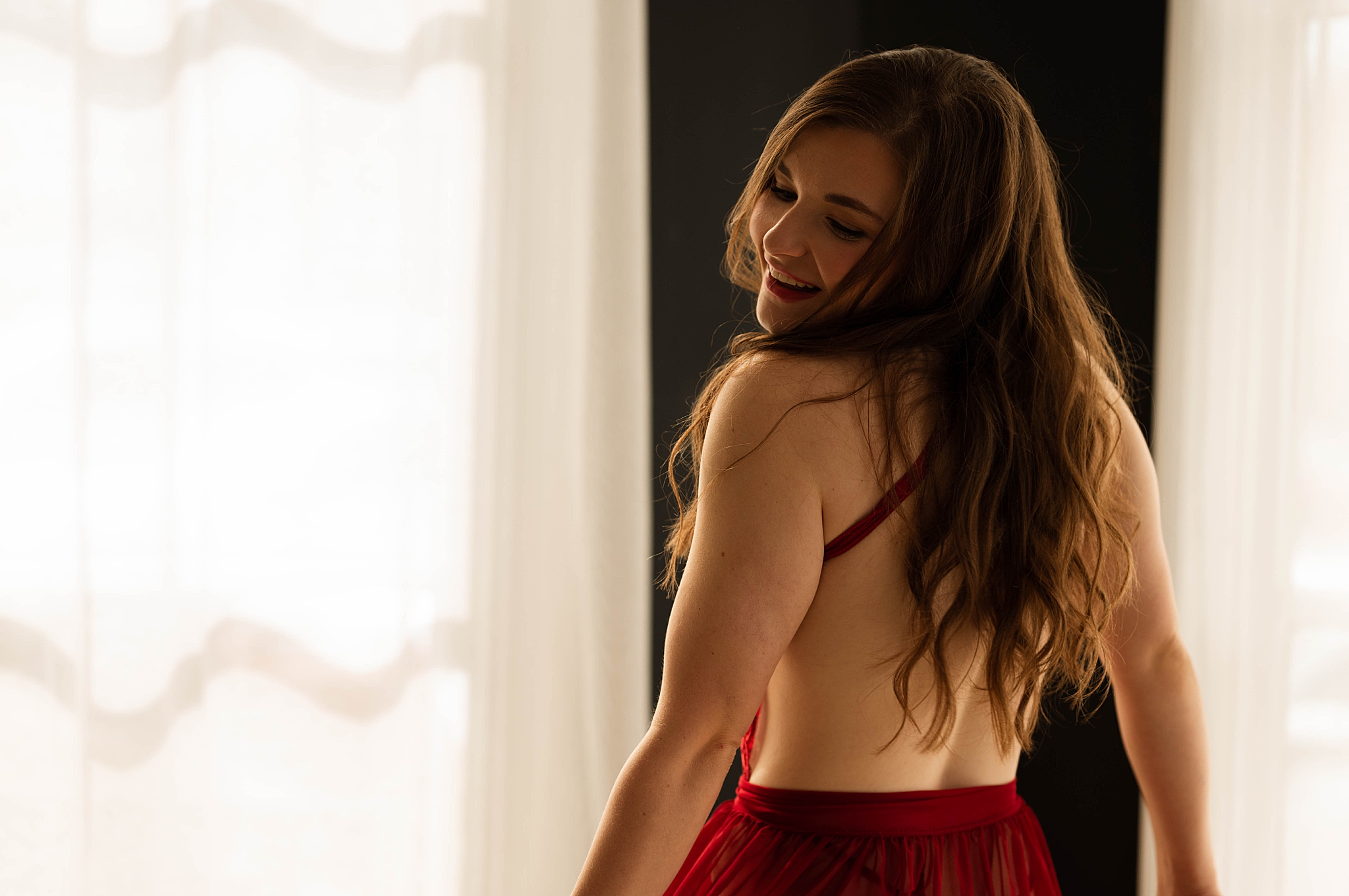 lady looks over shoulder in dark red skirt by Virginia boudoir photographer