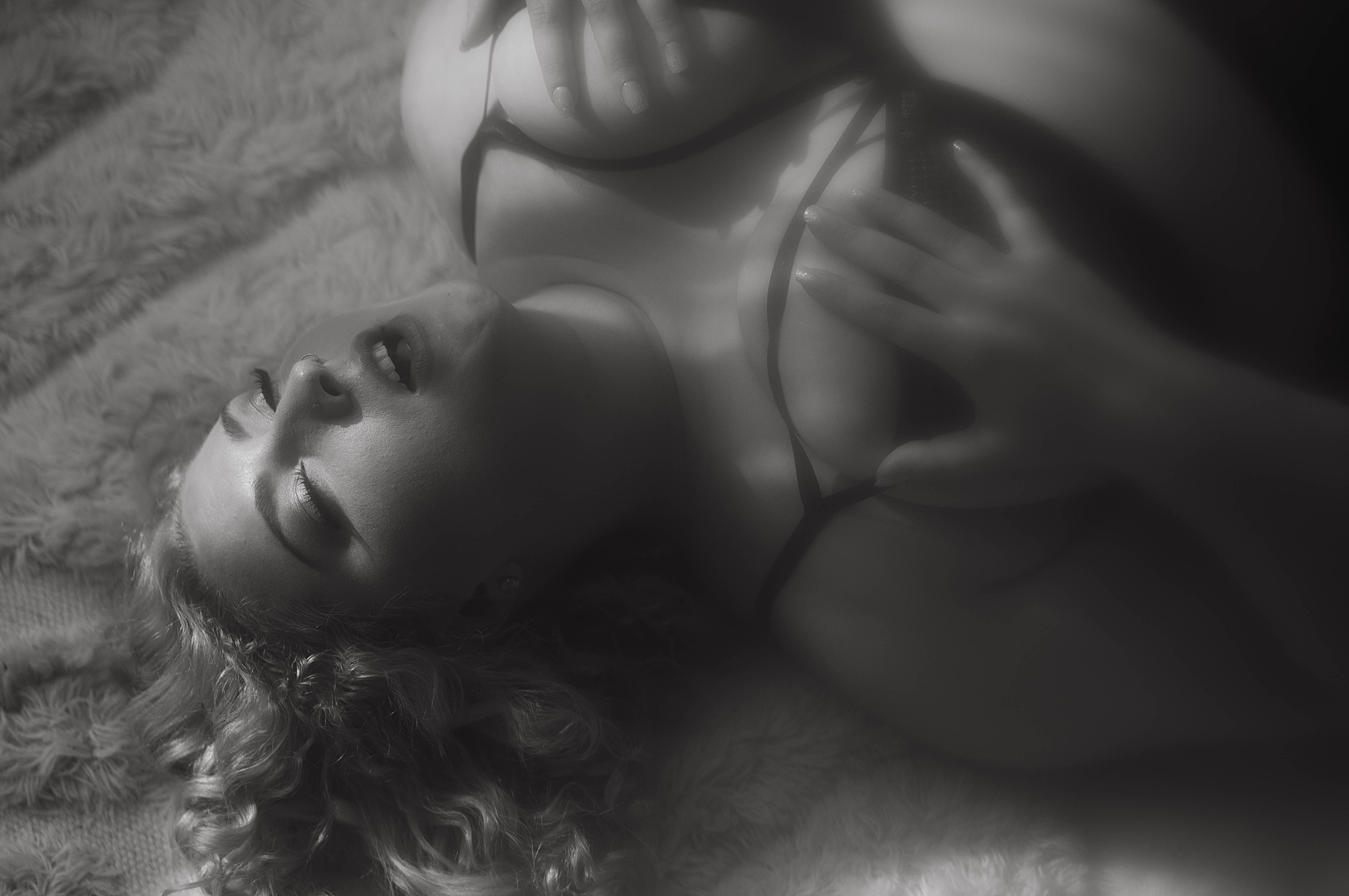 curly-haired beauty grabs chest while laying on ground for Virginia boudoir photographer