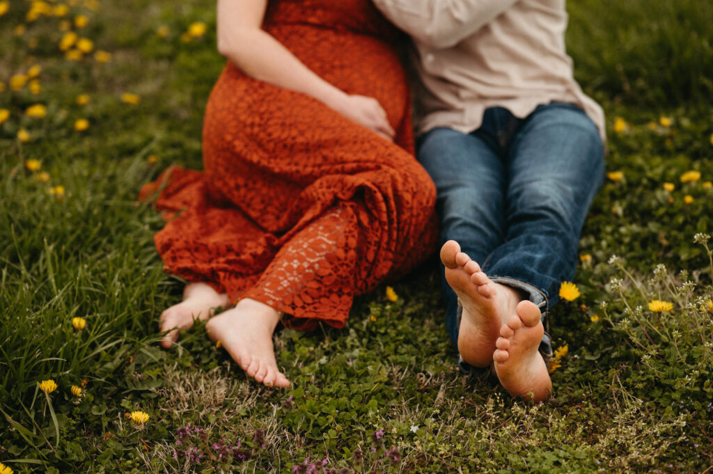 nature maternity shoot couple together sitting in the grass toes
